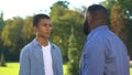 Afro-american dad scolding teenage son outdoors, family conflict, communication Royalty Free Stock Photo