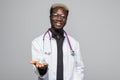 Afro american Doctor holding pills in hands isolated on gray background Royalty Free Stock Photo