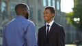 Afro-american father greeting son in suit outdoors university, prom celebration