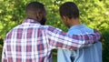 Afro-american father hugging son outdoors smiling each other, family connection