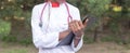 Afro American female doctor, twenty-seven years old, in a white coat, with a phonendoscope, writes a pen into a folder Royalty Free Stock Photo