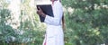 Afro American female doctor, twenty-seven years old, in a white coat, with a phonendoscope, writes a pen into a folder Royalty Free Stock Photo