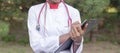 Afro American female doctor, twenty-seven years old, in a white coat, with a phonendoscope, writes a pen into a folder for papers Royalty Free Stock Photo