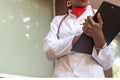 Afro American female doctor, twenty-seven years old, in a white coat, with a phonendoscope, writes a pen into a folder Royalty Free Stock Photo