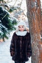 Afro american girl wearing in fur coat and knitted white hat in park in winter sunny day Royalty Free Stock Photo