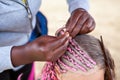 Afro American hairdresser hands made pink dreadlocks in African style for young European girl