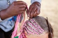 Afro American hairdresser made plaits in African style for young Caucasian girl, close-up Royalty Free Stock Photo