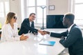 Afro american investment advisor shaking hands with smiling man while consulting with young couple about financial savings Royalty Free Stock Photo
