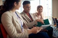 Afro-american male pointing with his pinkie finger detail in script at business conference to his asian female colleague, smiling