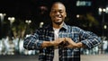 Afro american man african guy standing in night city affectionate romantic portrait looking at camera make heart shape Royalty Free Stock Photo