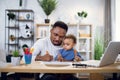 Afro american man carrying son and working on laptop Royalty Free Stock Photo