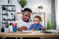 Afro american man carrying son and working on laptop Royalty Free Stock Photo