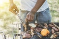 Afro american man cooking meat on barbecue - Chef putting some sausages on grill in park outdoor - Concept of eating outdoor Royalty Free Stock Photo