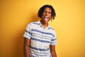 Afro american man with dreadlocks wearing striped shirt over isolated yellow background sticking tongue out happy with funny Royalty Free Stock Photo