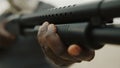 Afro-American man reloads pump action shotgun. Close up.