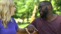 Afro-american man sitting on bench with woman, trying to impress her, first date