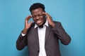 Afro american man with strict headache in studio on blue isolated background