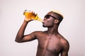 Afro american man in sunglasses and summer clothes drink cold fresh summer drink in bottle isolated on white background Royalty Free Stock Photo