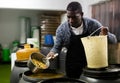 Afro-american man takes olives from barrel with colander Royalty Free Stock Photo