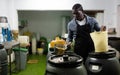 Afro-american man takes olives from barrel with colander Royalty Free Stock Photo