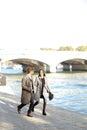 Afro american man and caucasian girl running near Seine bridge, Paris. Royalty Free Stock Photo
