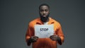 Afro-american prisoner holding Stop sign, racial discrimination, persecution