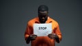 Afro-american prisoner holding stop sign, racial discrimination, persecution