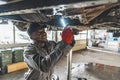 Afro-American serviceman replacing a clutch on a car at work, car repair concept