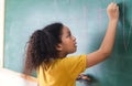 Afro american student girl writing on green chalkboard. Education, elementary school, learning, School children education concept