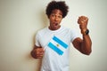 Afro american tourist man holding Argentinian Argentina flag over isolated white background annoyed and frustrated shouting with Royalty Free Stock Photo