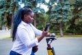 Afro american woman activate and prepay a rental e-scooter or an e-bicycle on the street Royalty Free Stock Photo