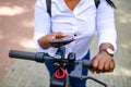 Afro american woman activate and prepay a rental e-scooter or an e-bicycle on the street Royalty Free Stock Photo