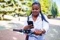 Afro american woman activate and prepay a rental e-scooter or an e-bicycle on the street Royalty Free Stock Photo