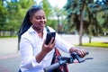 Afro american woman activate and prepay a rental e-scooter or an e-bicycle on the street Royalty Free Stock Photo