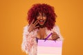 Afro american woman at shopping holding pink bag isolated on orange background on black friday holiday. Copy space for Royalty Free Stock Photo