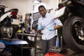 Afro american worker inspects the wheel of a motorcycle