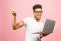 Afro american young man using laptop over isolated pink background surprised with an idea or question pointing finger with happy Royalty Free Stock Photo