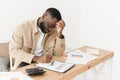 Afro american young man very frustrated with family budget problems while checking bank papers or tax forms. Royalty Free Stock Photo