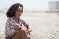 Young woman sitting on a gravel stone ground outside playing her acoustic guitar looking away Royalty Free Stock Photo