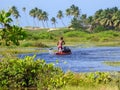 Afro-brazilian man rowing a canoe on the river near the Hippie Village in Arembepe - Bahia, Brazil