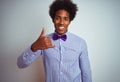 Afro business man wearing striped shirt and purple bow tie over isolated white background doing happy thumbs up gesture with hand Royalty Free Stock Photo