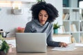 Afro business woman working with computer while consulting some invoices and documents in the kitchen at home Royalty Free Stock Photo