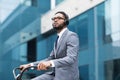 Afro businessman in earphones riding on bike