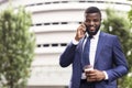 Afro Businessman Having Coffee And Talking On Mobile Phone Outdoors Royalty Free Stock Photo