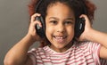 Afro child girl in big headphones at gray studio background