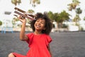 Afro child playing with wood toy airplane on the beach - Little kid having fun during summer holidays