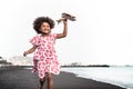 Afro child playing with wood toy airplane on the beach - Little kid having fun during summer holidays
