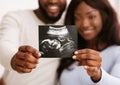 Afro couple demonstrating ultrasound image of their baby