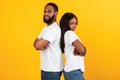 Afro couple standing back to back, yellow orange studio wall Royalty Free Stock Photo