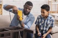 Afro Dad Teaching Preschool Son To Use Electric Drill At Home